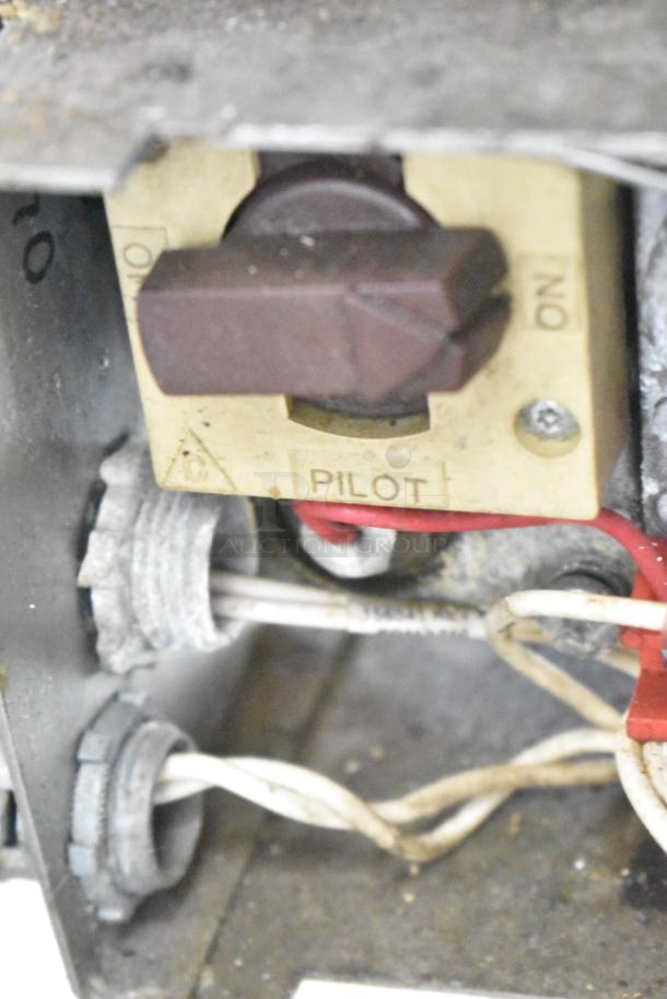 Close-up of control panel on a stainless steel commercial braising pan, showing pilot indicator and wiring, in used condition.