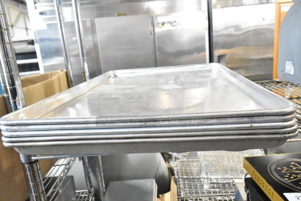 5 full-size metal baking pans, stacked, in good used condition. Ideal for commercial kitchens.