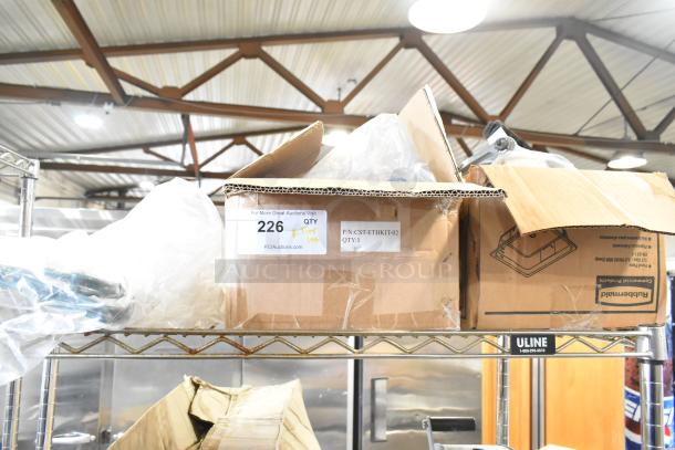 Cardboard boxes with various items including Rubbermaid amber drop-in bins, cables, and brackets, labeled for auction.