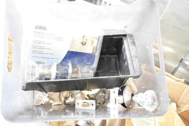 Clear plastic bin containing First Watch passage door latch set, glass door knobs, and a black poly bin.