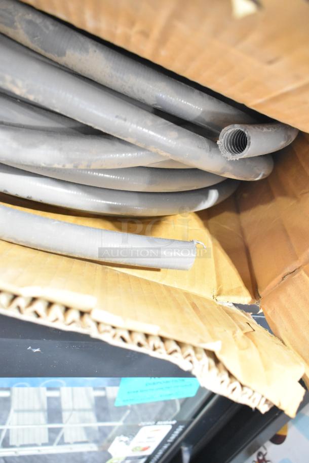 Coiled Global Manufacturing EF-INTERLOCK hose, gray, in original packaging, new condition, corrugated texture visible.