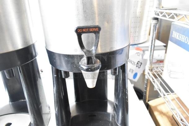 Two metal countertop beverage holder dispensers, black bases, "DO NOT SERVE" label on tap handle, used condition.