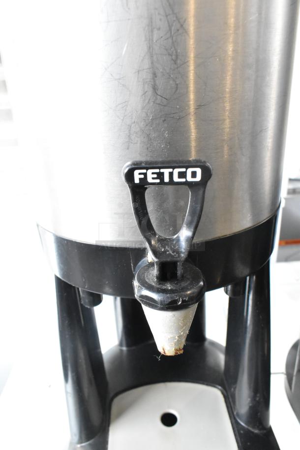 Fetco metal beverage holder dispenser with black plastic base, used condition.