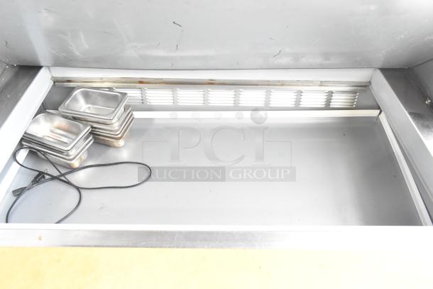 Beverage Air SPE48-18M stainless steel prep table interior. Includes small pans, cord visible. Commercial grade, 115V.