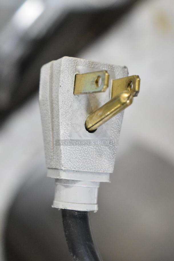 Close-up of a 115-volt plug, part of a True GDM41SL48-HC-LD commercial cooler, showing textured surface and brass prongs.
