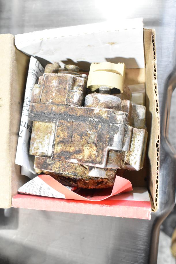 Rusted mechanical component in a cardboard box, part of a lot with kegerator hoses and couplers, showing wear and age.