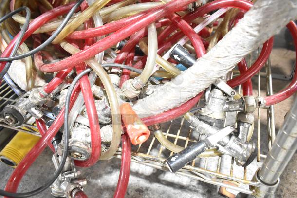 Assorted kegerator hoses and couplers, various colors, used condition, tangled on a metal wire shelf.