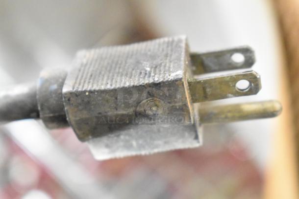 Close-up of a metal commercial countertop warmer plug, showing a 115-volt, 1-phase connector in used condition.