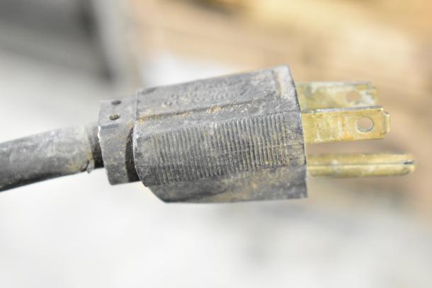 Close-up of a metal countertop warmer plug, showing a worn, three-prong connector. 115 volts, 1 phase power.