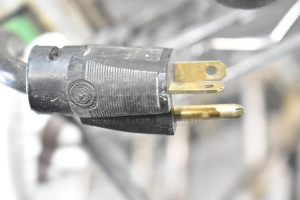 Close-up of a plug for the Roundup TBS-1X 208V commercial food steamer, showing three-prong design.