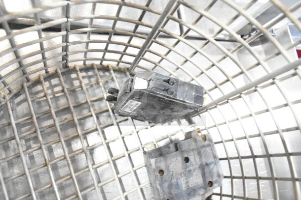 A fry basket holding circuit components, showing metal grid design and wear. Items include visible labels and markings.