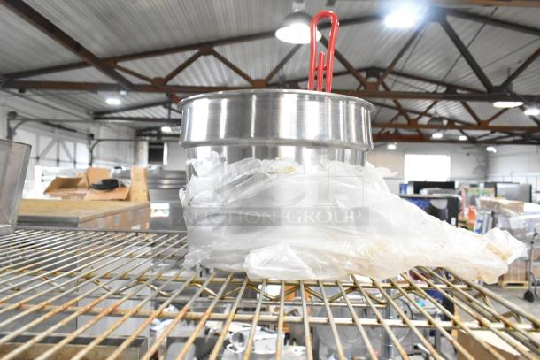 Alt text: "Lot of various items including a cup dispenser and fry basket on metal shelf, wrapped in plastic, industrial setting."