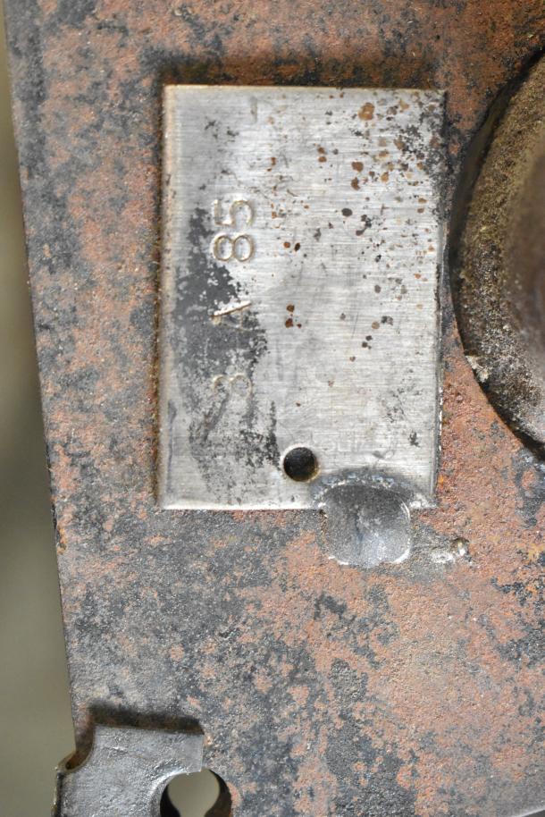 Close-up of a weathered stainless steel unit showing a metal plate with engraved numbers "385". Signs of rust are visible.