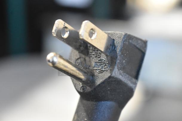 Close-up of a power plug suitable for the Imbera EVC04 Mini Cooler Merchandiser, showing prongs and labels.
