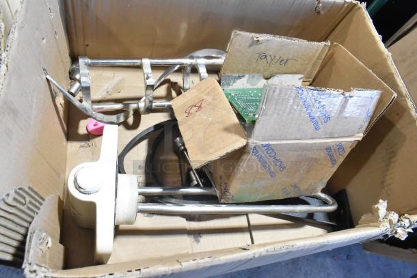 Lot of various ice cream machine parts, including auger, in a cardboard box. Visible labels: "Taylor." Mixed condition.