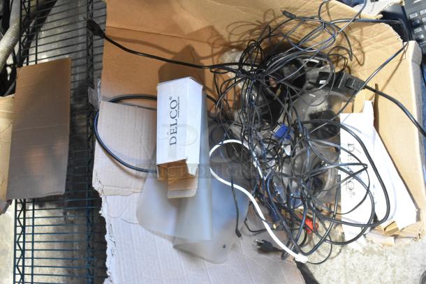 Lot of miscellaneous electronics in a box, includes cables, a DELCO labeled box, and various unidentified devices. Condition unknown.