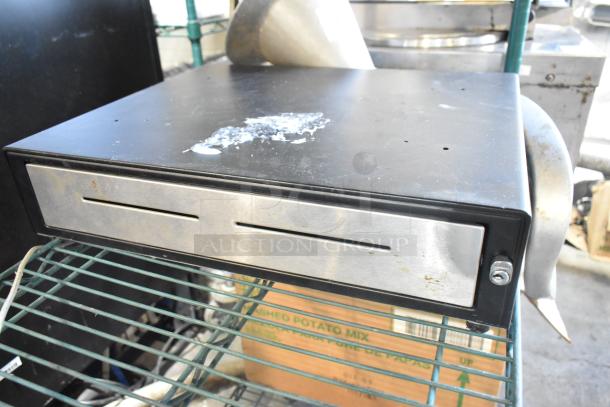 Metal cash drawer with a black top and stainless steel front, showing signs of wear. Part of a 10-item auction lot.