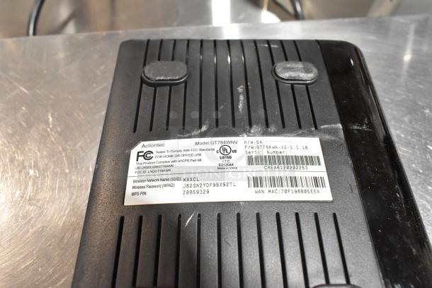Actiontec GT784WN router label showing FCC and UL certification, SSID, and WPA password details. Used condition.