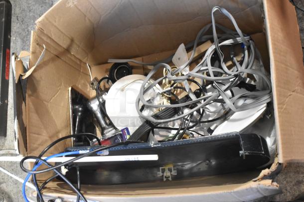 Cardboard box containing mixed electronic items, visible wires, and components. Includes metal cash drawer and unidentified devices. Condition is used.