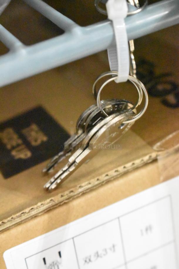 Keys attached to a metal shelf with a zip tie above a cardboard box.