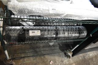 Two Lavex 844LDM35bLKBEV black anti-fatigue floor mats, wrapped for shipping, labeled "292," on a metal shelf.