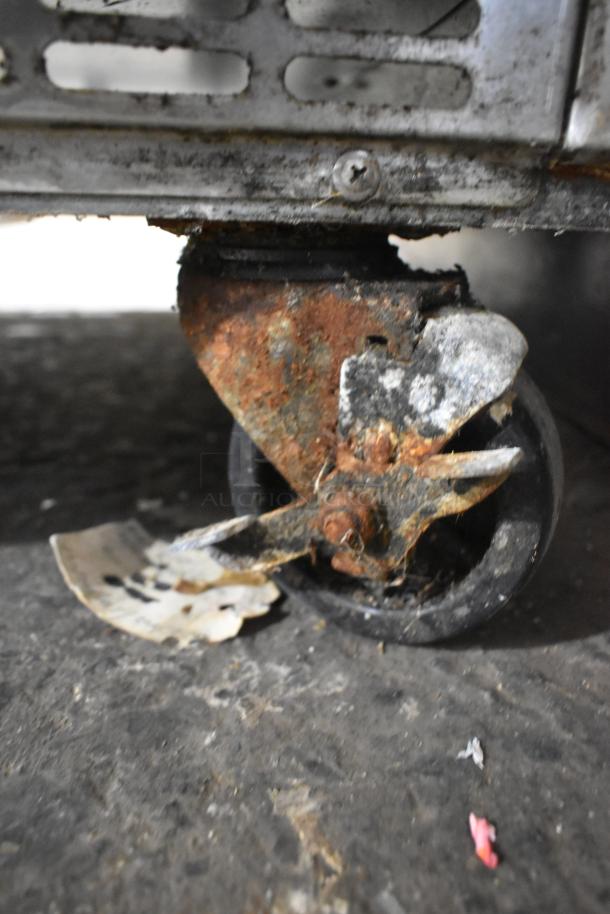 Rusted caster wheel of Everest stainless steel commercial sandwich salad prep table. Signs of wear and use visible.