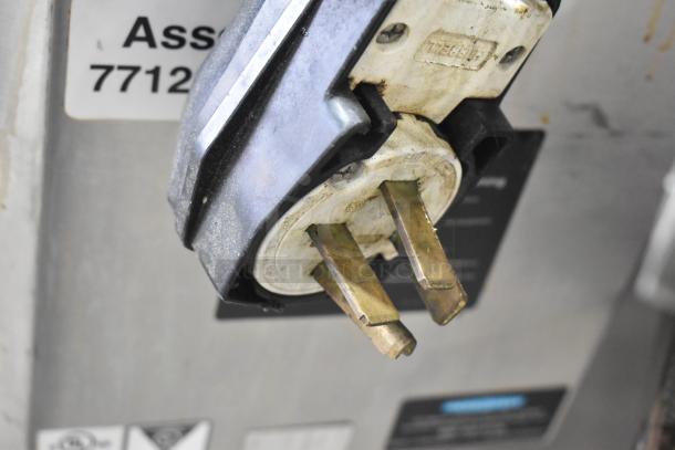 Close-up of a plug on the back of a Turbochef HhC2020 stainless steel commercial electric conveyor oven. Tags and labels are visible.