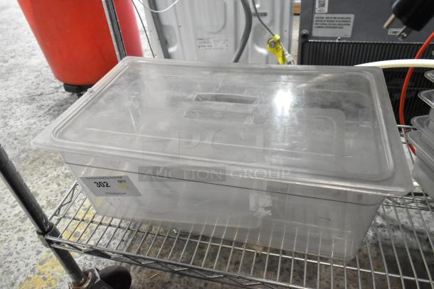 Lot of 6 clear poly bins with lids, visible wear. Item 302 tag indicates auction status. Ideal for storage.