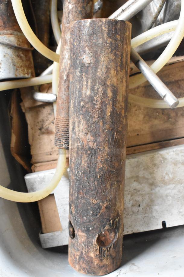 Lot of various metal items in a bin, featuring rusted cylindrical pieces, tubes, and mechanical parts. Well-worn condition.