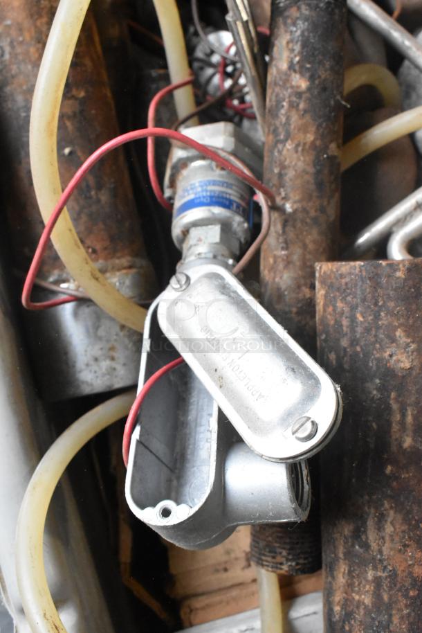 Lot of assorted metal items in a bin, including rusted pipes, a metal junction box, hoses, and wires. Some wear visible.