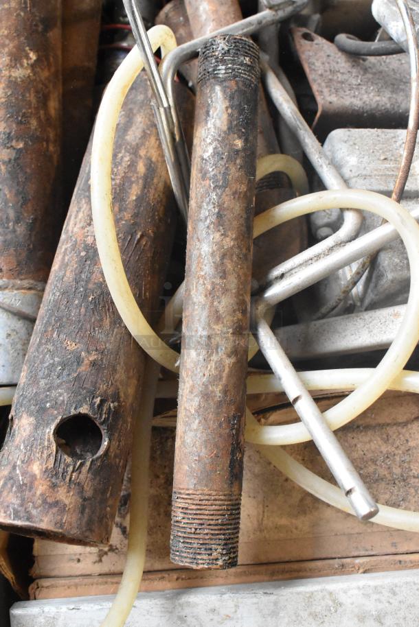 Lot of various metal pieces in a bin, showing rusted pipes, rods, and flexible tubing, indicating used condition.