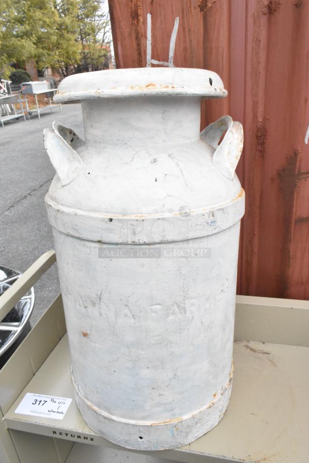 Tan metal 3-tier cart with commercial casters, featuring a weathered metal jug on top. Tag reads "317 1/2 QTY".