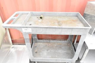 Gray poly 2-tier cart with commercial casters, some surface rust, features label "319" for inventory tracking, good condition.