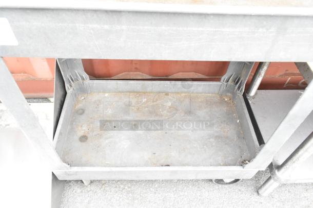 Gray poly 2-tier cart with commercial casters, showing signs of use, suitable for industrial settings.