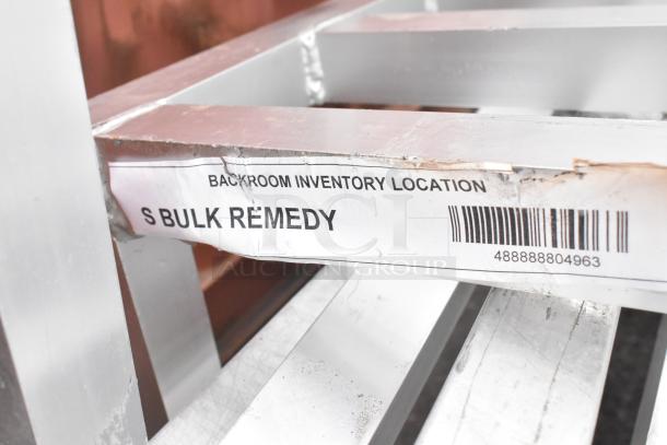 15 metal dunnage racks, silver, sturdy for storage. Label: "Backroom Inventory Location S Bulk Remedy" with barcode.