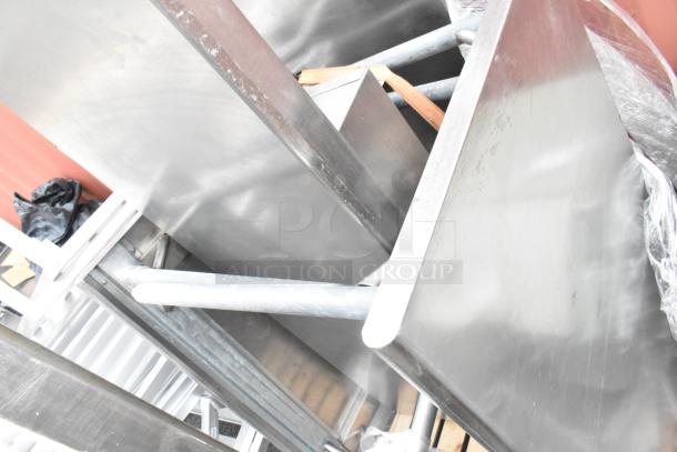 Three stainless steel tables, stacked, showing surfaces and legs. Appears in used condition. No visible markings or tags.