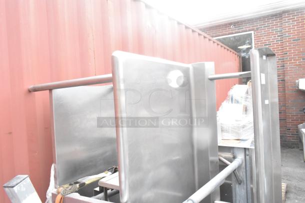 Three stainless steel tables with sturdy construction. Slight wear visible. Outdoor storage, ready for industrial use.