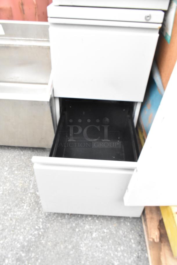 Two gray metal 2-drawer filing cabinets, top drawer open. Used condition, sturdy build, ideal for office storage.