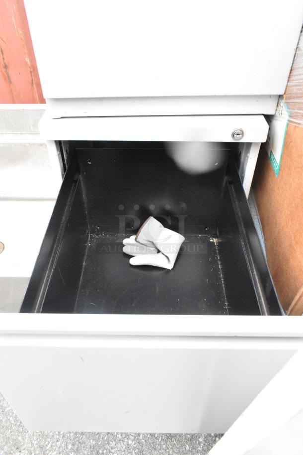 Two gray metal two-drawer filing cabinets, good condition, one drawer open. Includes gray work glove inside drawer.