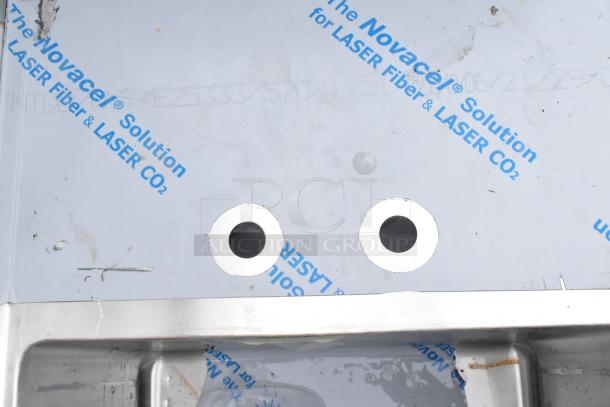 Stainless steel single bay sink with protective film, minor scratches, two pre-drilled faucet holes, and laser-related markings.