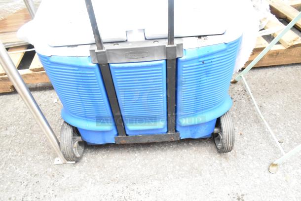 Rubbermaid white and blue poly portable ice bin, sturdy design, wheels for mobility, slight wear visible.