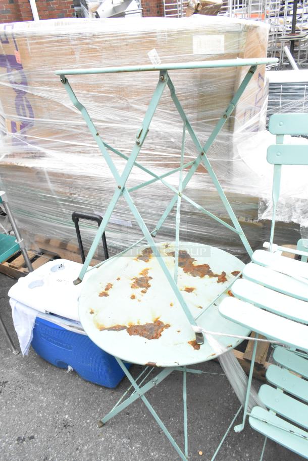 Six metal items including two rusted folding chairs and tables; light green finish, signs of wear; packaged wooden benches nearby.