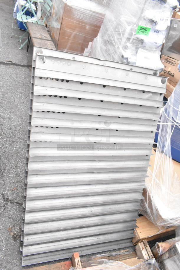 Two corrugated metal panels, silver in color, stacked on a pallet. Panels have evenly spaced holes for mounting.