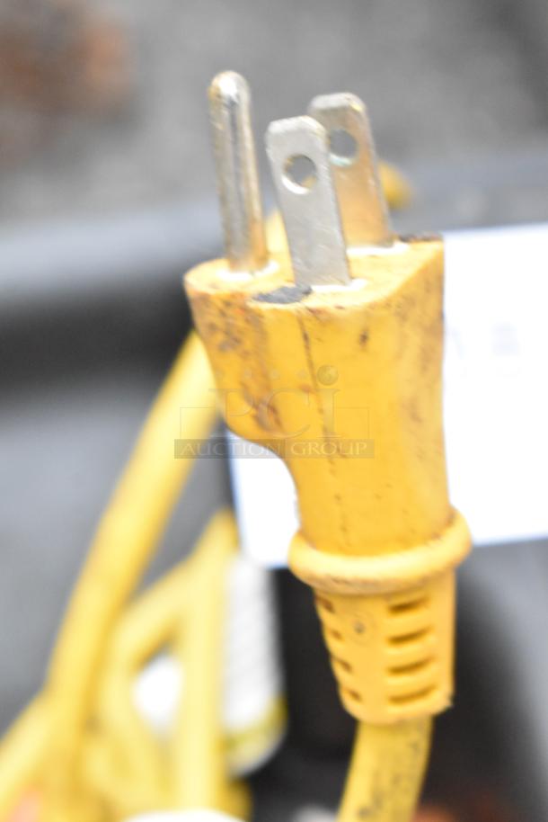 Close-up of a yellow plug for Tornado 98774 air mover fans. Visible wear on the plug, 120 volts, 1 phase.