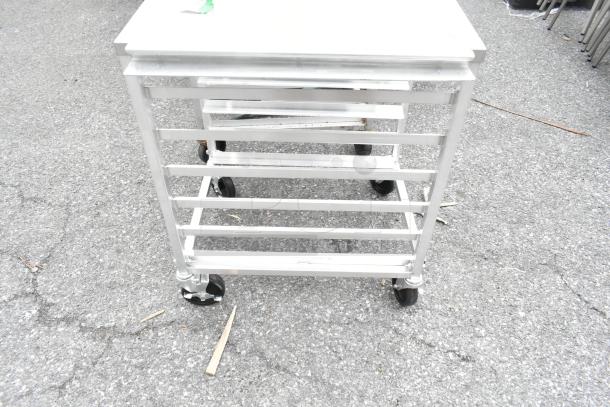 Regency 600upr6wtels aluminum undercounter bun/sheet pan rack with stainless steel top, 6-pan capacity, on wheels.