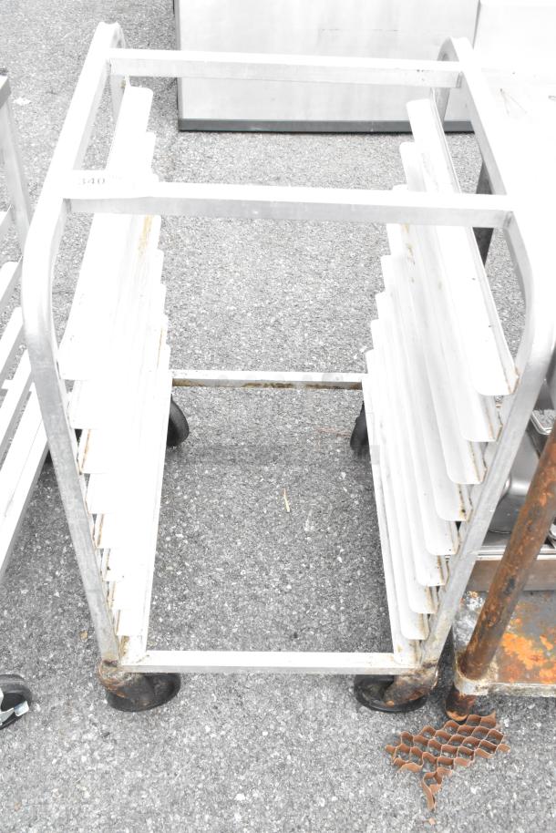 Metal bun sheet pan rack on commercial casters, with multiple slots for storage. Visible rust and wear on the frame.