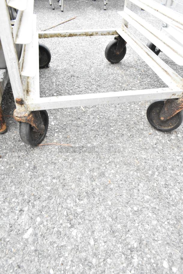 Metal bun/sheet pan rack on commercial casters, displays signs of rust and wear, suitable for commercial kitchens.