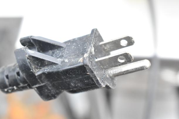 A dusty black electrical plug with standard prongs and a plastic casing.