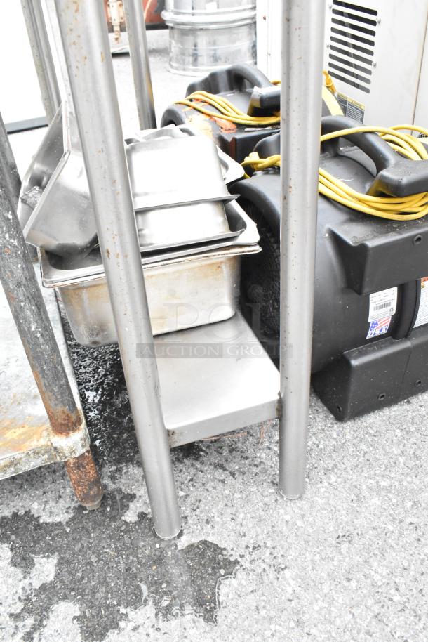 Stainless steel table with metal under-shelf and backsplash, includes two Dayton air mover fans; visible wear on metal.