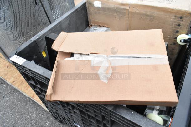 Cardboard box containing scratch and dent items like sink and dolly, taped and placed in a black crate.
